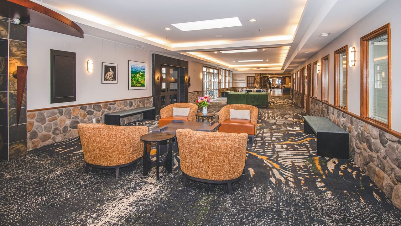 Interior of a lounge area with chairs, tables, stone walls, and artwork.