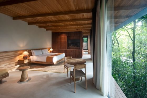 Modern bedroom with wooden design elements and a view of greenery in West Bungalows at Hotel Rio Perdido