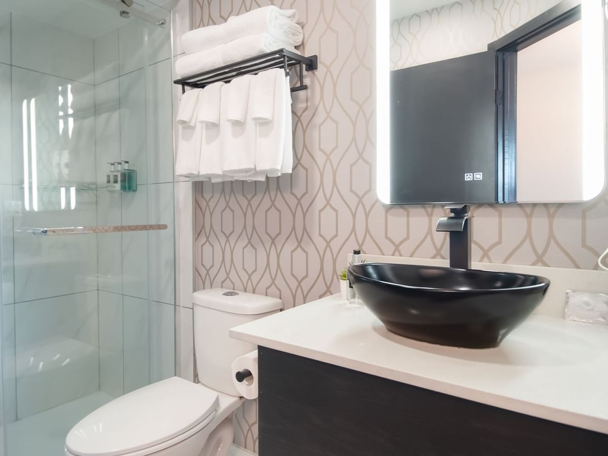 Hotel bathroom with toilet, shower, sink, towels and soap