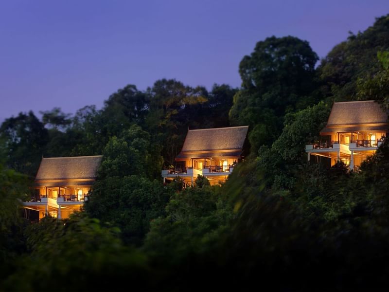 Pangkor Laut Resort on a hillside, illuminated at dusk amidst lush trees, creates a serene atmosphere