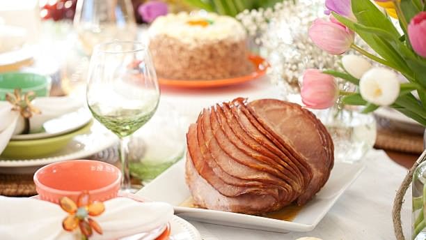 Easter Brunch spread with ham, cake, and flowers on a table.