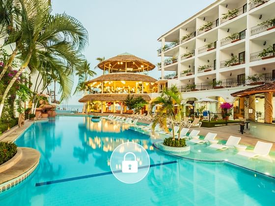 Sparkling blue swimming pool flanked by palm trees and white lounge chairs at Playa Los Arcos Beach Resort & Spa