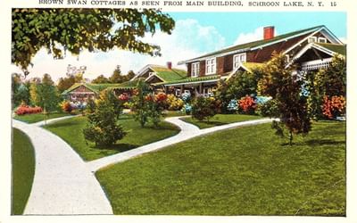 Vintage postcard depicting colorful gardens and pathways at Brown Swan Cottages in The Lodge at Schroon Lake