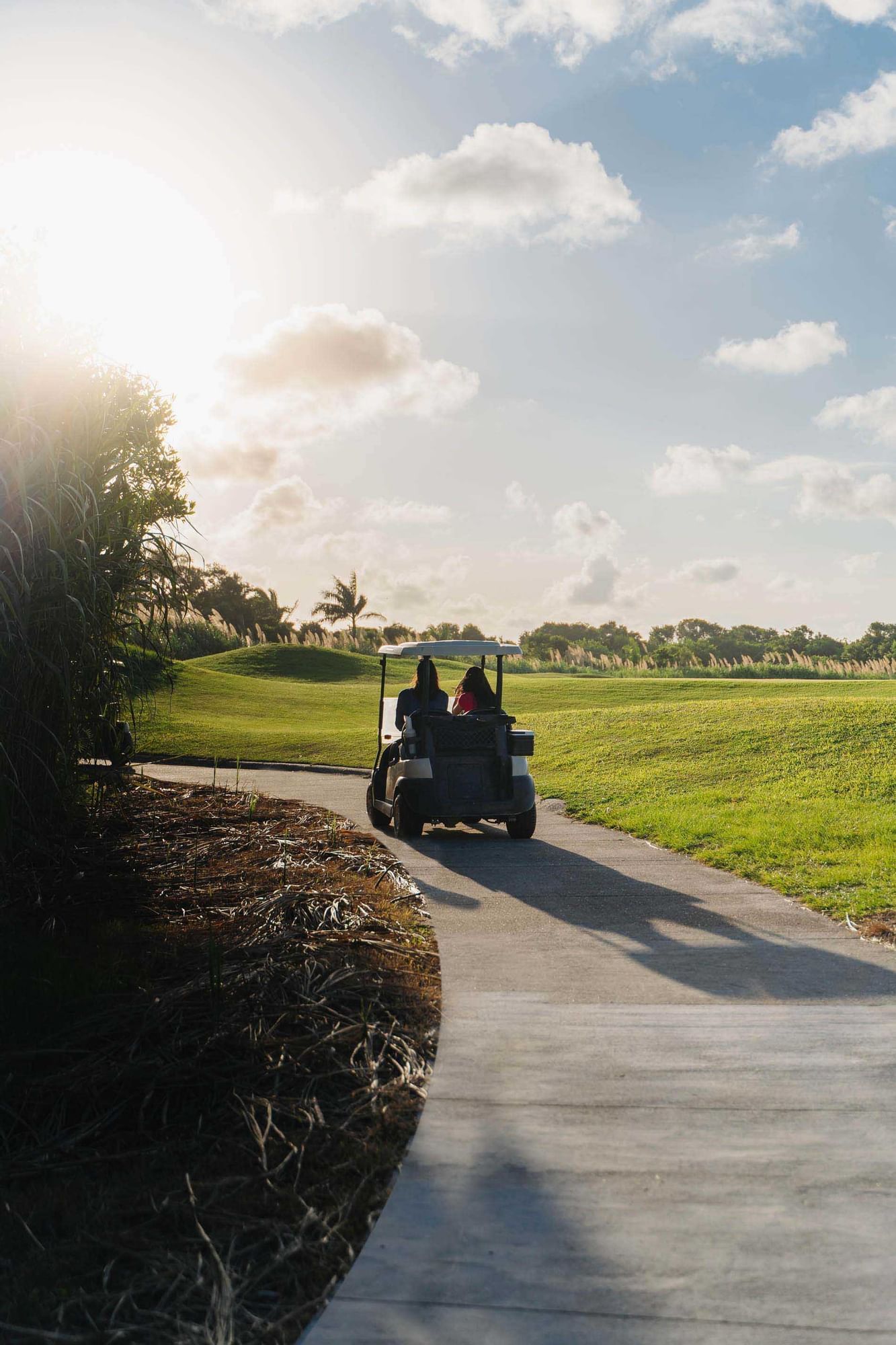 Couple riding a golf cart outdoors at golf course near Indura Beach & Golf Resort