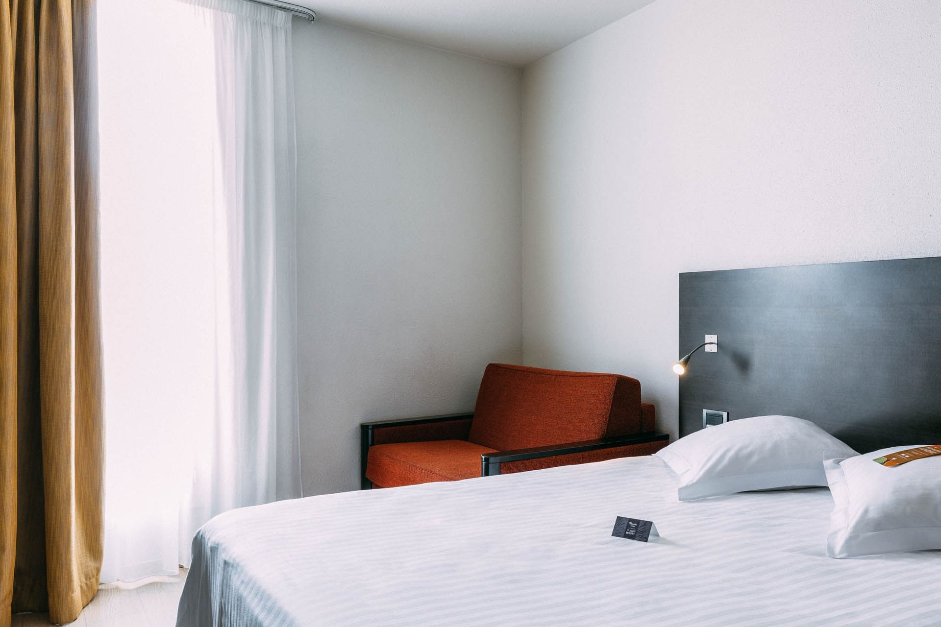 Lit king-size et fauteuil de salon dans une chambre à l'Escale Oceania Marseille