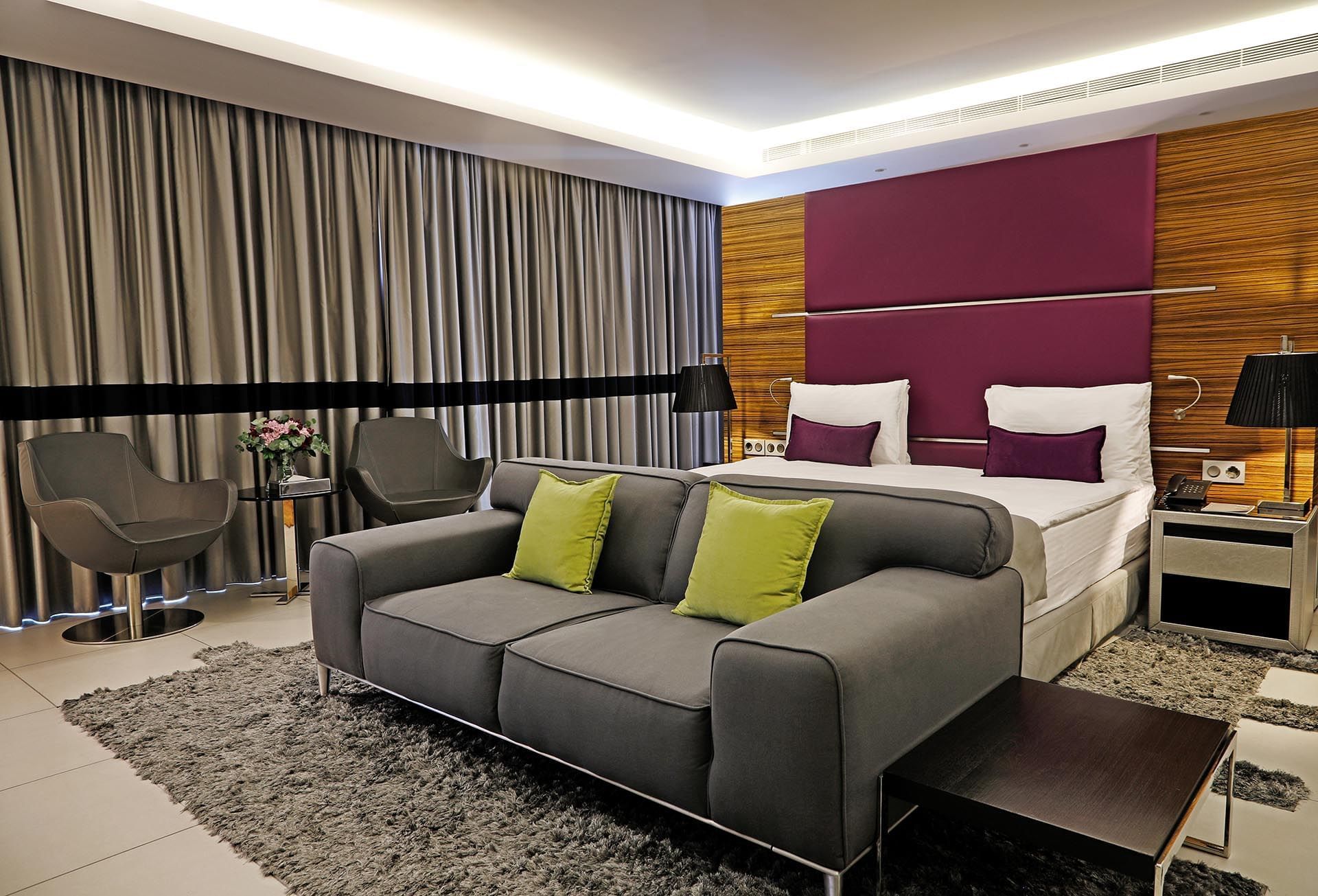 Junior Suite features Grey sofa by swiveling chairs under a purple headboard at Warwick Stone 55 - Beirut