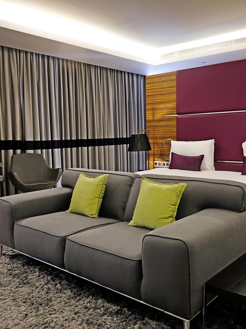 Junior Suite features a Grey sofa by swiveling chairs under a purple headboard at Warwick Stone 55 - Beirut
