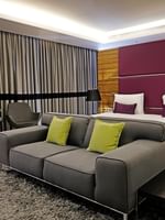 Junior Suite features a Grey sofa by swiveling chairs under a purple headboard at Warwick Stone 55 - Beirut