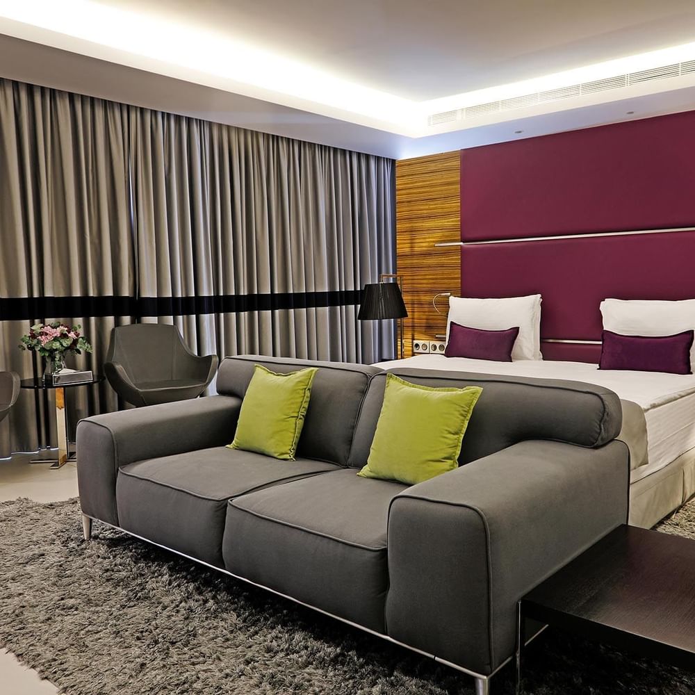 Junior Suite features a Grey sofa by swiveling chairs under a purple headboard at Warwick Stone 55 - Beirut