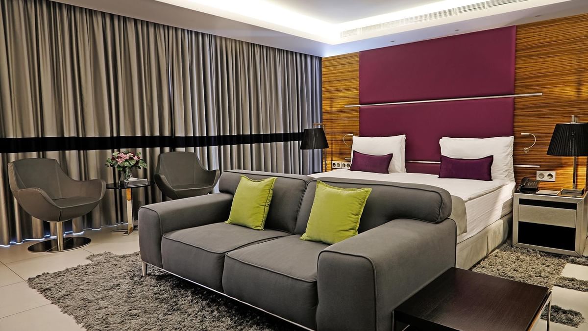 Junior Suite features a Grey sofa by swiveling chairs under a purple headboard at Warwick Stone 55 - Beirut