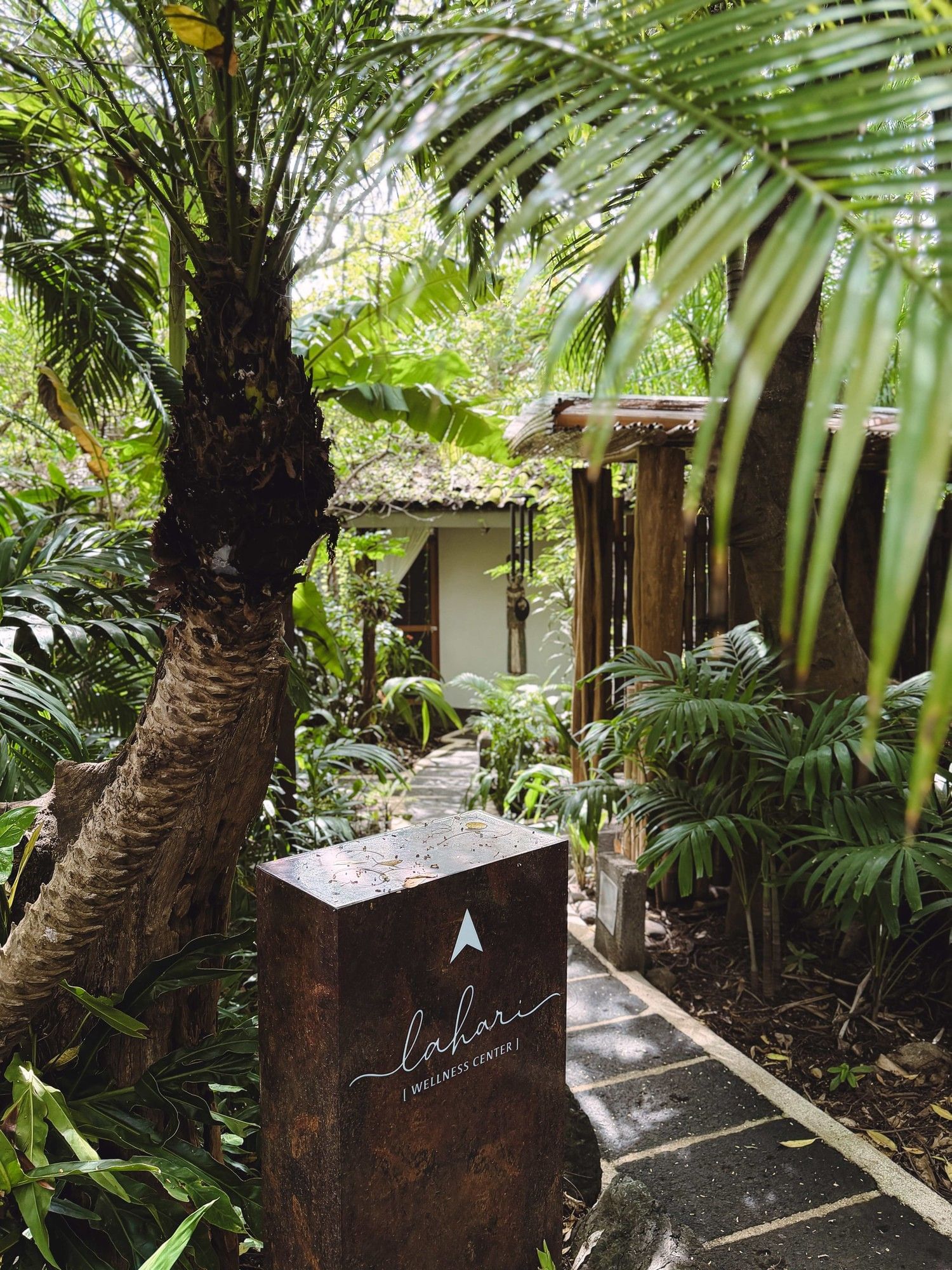 Lahari Wellness Center sign surrounded by lush tropical greenery and palm trees at Cala Luna Boutique Hotel