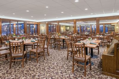 The dining room at Lake Placid Club Grandview is filled with wooden tables and chairs and features large windows