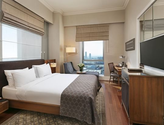 Titanic Business Kartal'da konforlu bir konaklama sunan lüks otel odası; geniş bir yatak, şık koltuklar, çalışma masası ve düz ekran televizyonla donatılmıştır.