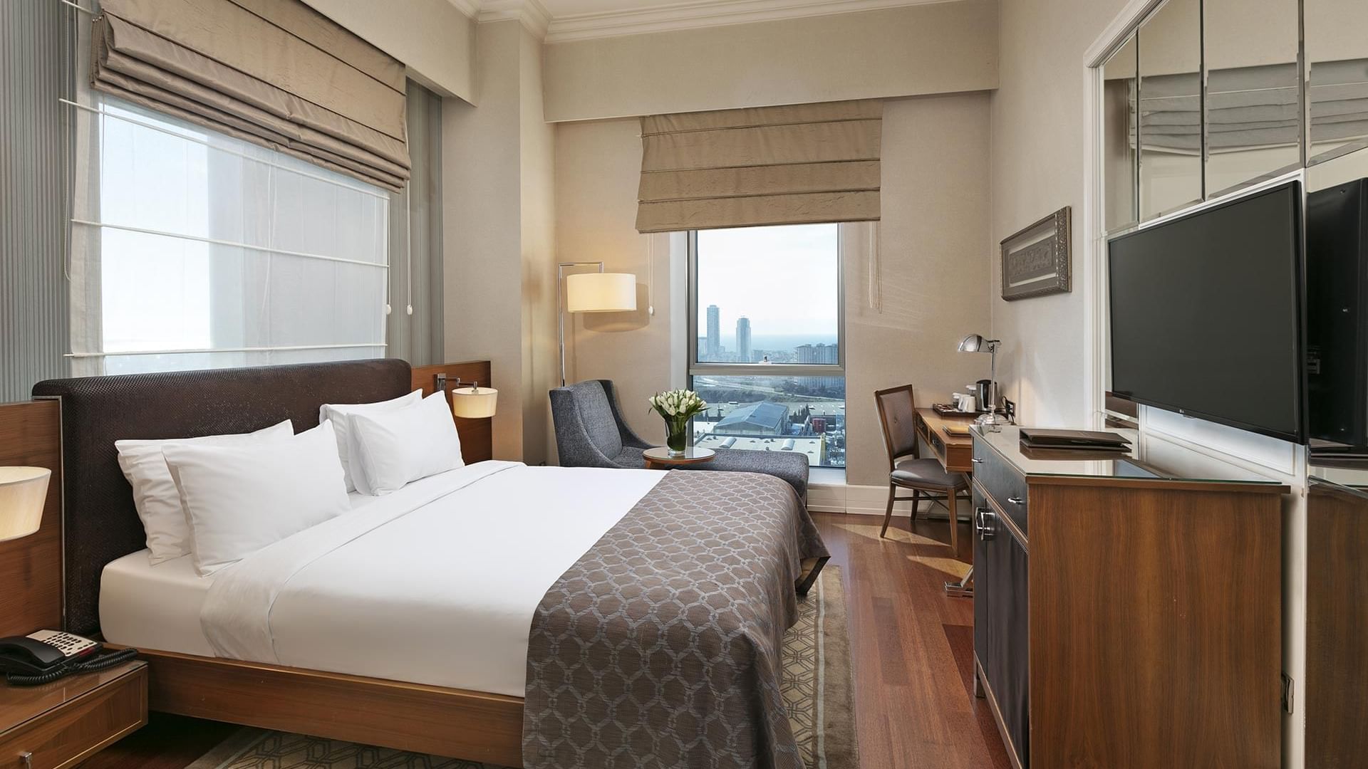 Double bed with a TV and work desk in Deluxe Room at Titanic Business Kartal