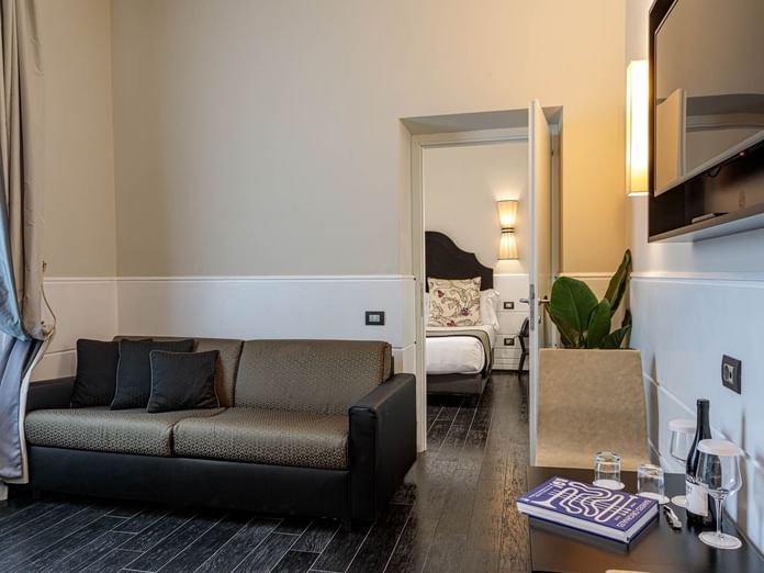 View of Family Room with a stylish sofa, bedroom view, TV, mini-bar, and elegant decor at The Independent Suites