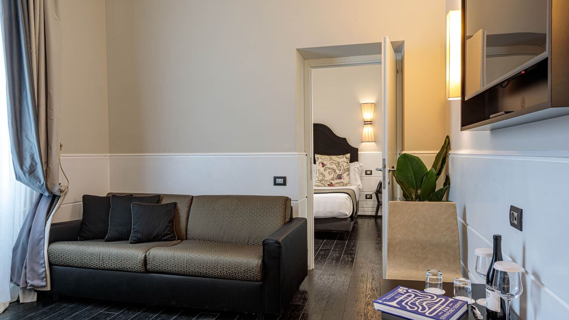 View of Family Room with a stylish sofa, bedroom view, TV, mini-bar, and elegant decor at The Independent Suites