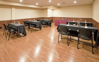 Classroom set-up in Oxford event room arranged with black chairs & tables over light wood floor space at Clayton Plaza Hotel