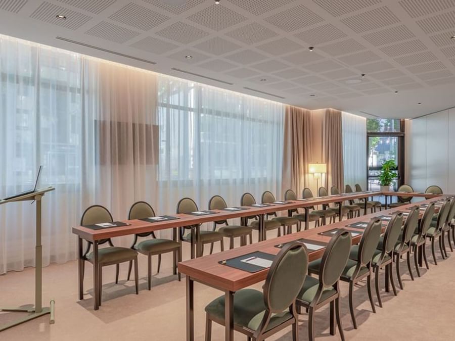Salle de réunion lumineuse avec tables en bois et chaises vertes disposées en configuration classe au Warwick Reine Astrid-Lyon