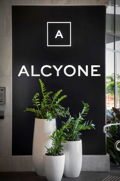 Hotel name at the entrance of Alcyone Hotel Residences with plant decor
