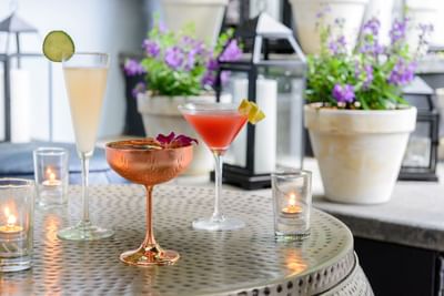 Romantic hotel in Greenwich with a fine dining restaurant serving colorful drinks by purple flowers at The J House Greenwich
