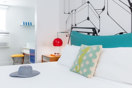 A Mid-century modern room at the Vagabond Hotel Miami with white decor, teal and red accents, king bed, & bed side table