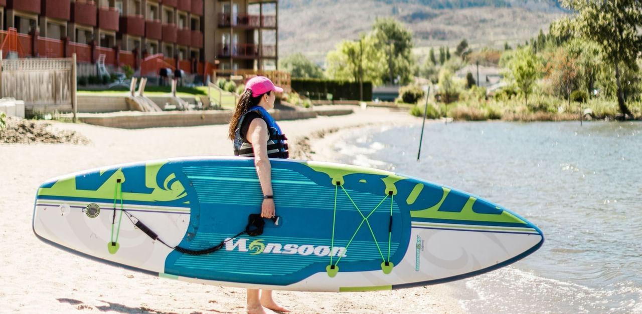 women holding a paddleboard on the beach