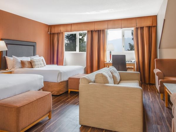 Hotel guest room with two queen beds and arm chairs