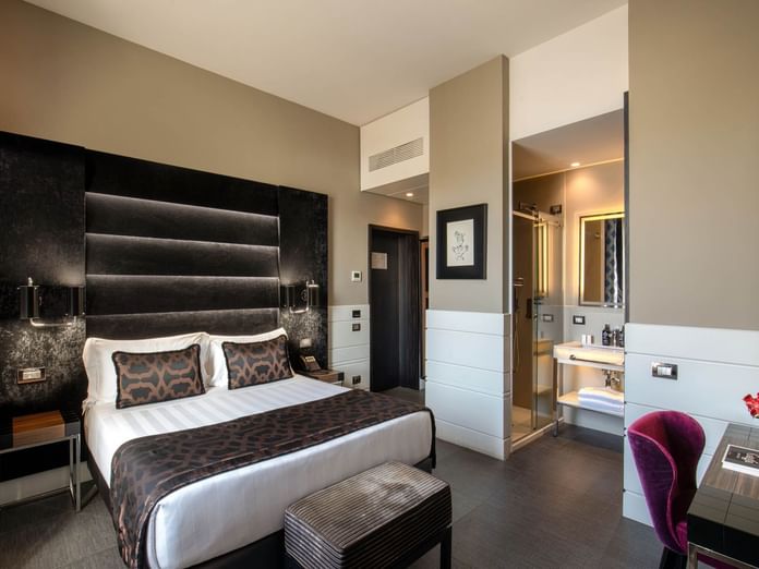 Bed with ottoman and work desk beside in Classic Room at The Glam Hotel