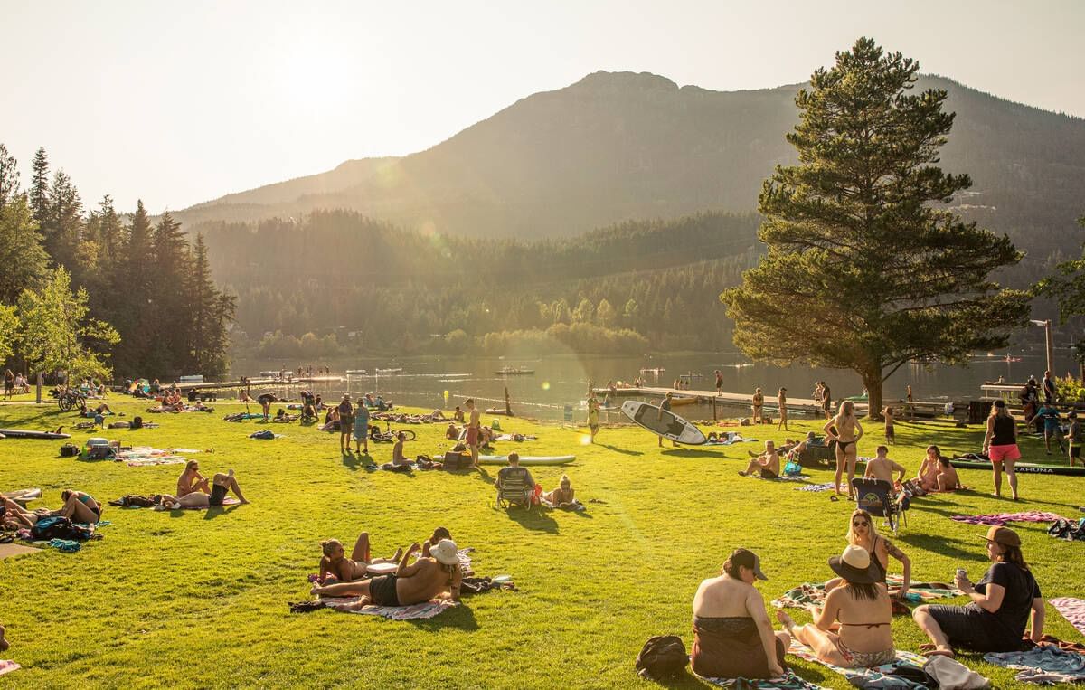 People relaxing on lakeside ground by Alta Lake near Blackcomb Springs Suites