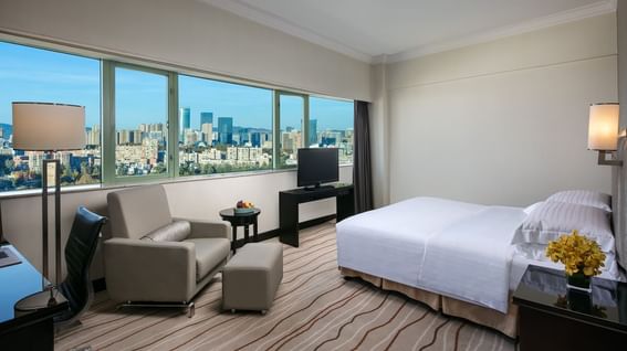 Cozy bed & sitting area with a city view in Crystal Club Suite at Park Hotel Group