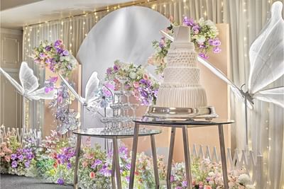 A spectacular wedding cake display with a champagne tower and a whimsical butterfly floral backdrop at Goodwood Park Hotel