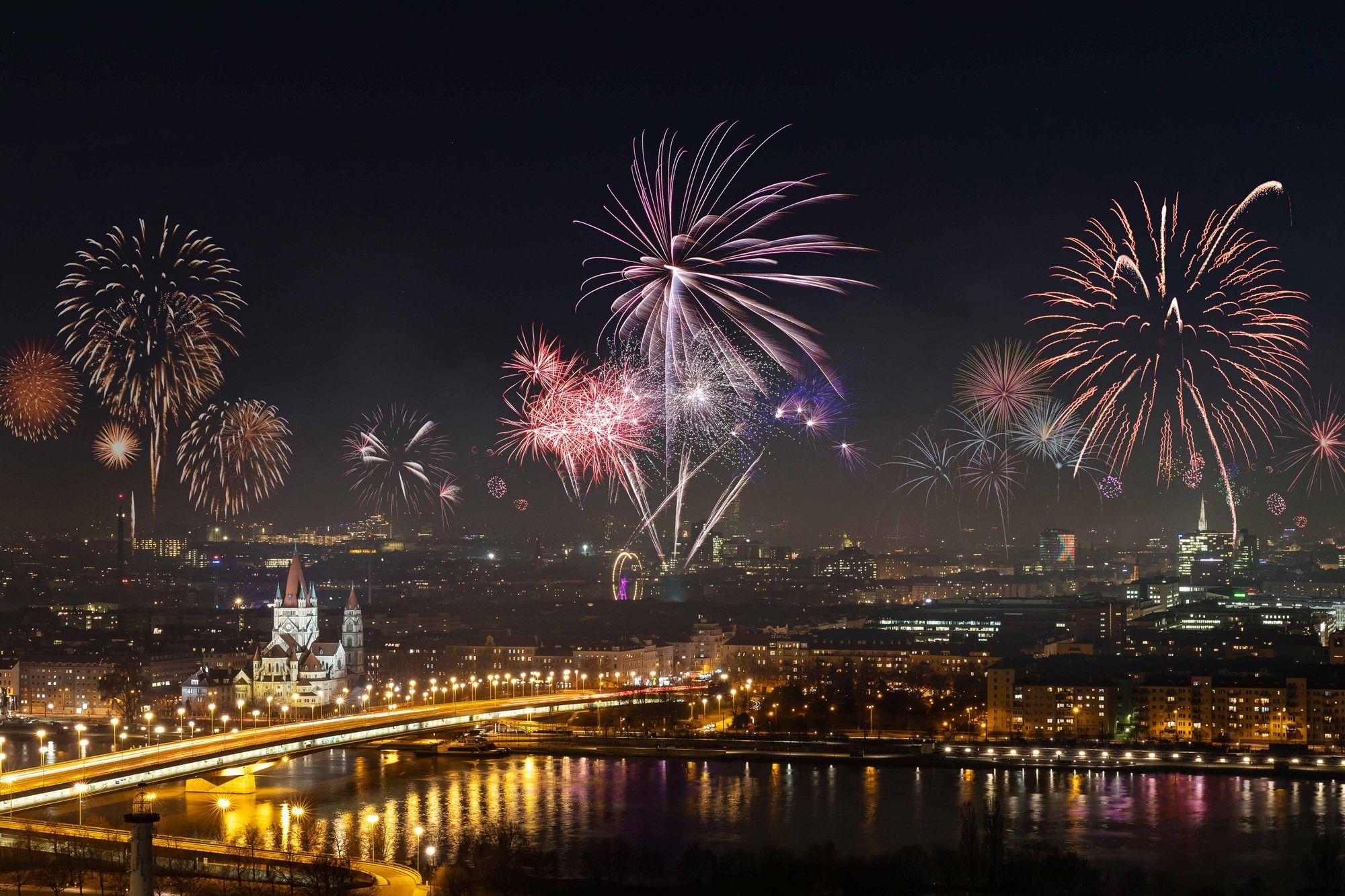 Fireworks over the Vienna skyline on New Year’s Eve, with a view of the Danube and the illuminated city.