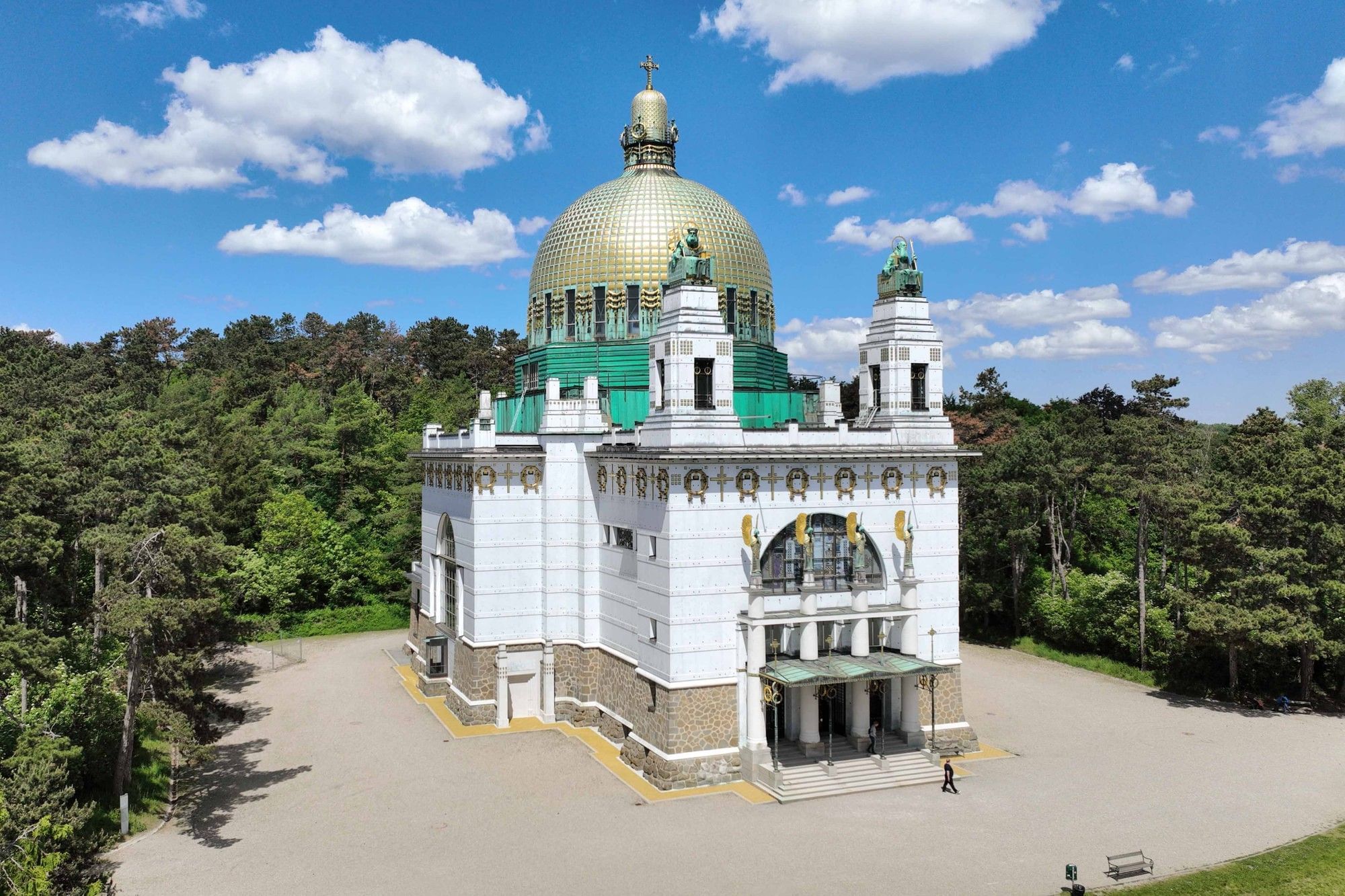 Kirche am Steinhof in Wien mit goldener Kuppel und Jugendstil Architektur in grüner Umgebung.