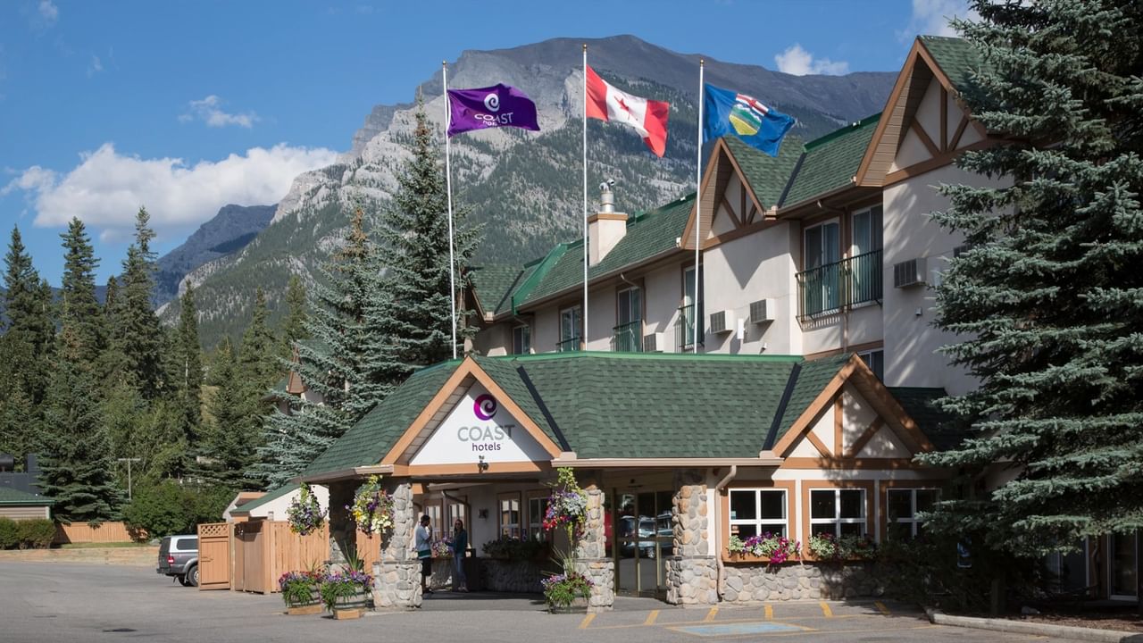 Three flags and mountain view outside the entrance of Coast Hotels in Canmore.