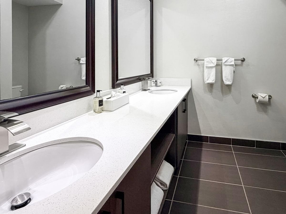 Bathroom with dual sinks, mirrors, and towels.