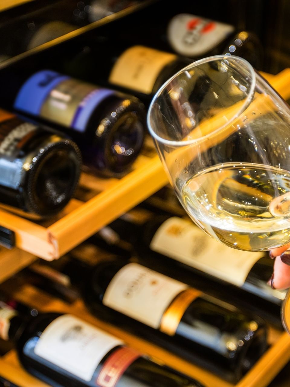 A hand holds a glass of white wine in Market @ La Marina at El Conquistador Resort