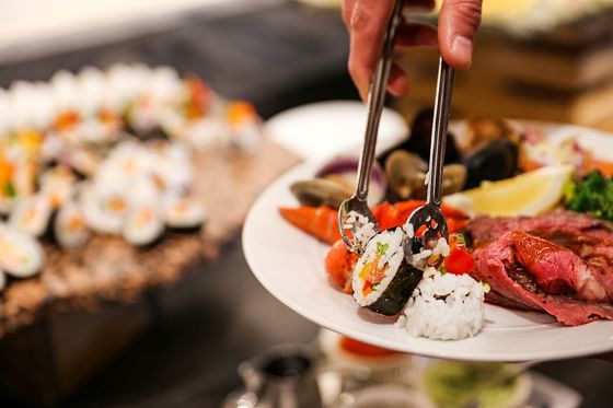 A person holding a plate of sushi and various other food items at Stein Eriksen Lodge