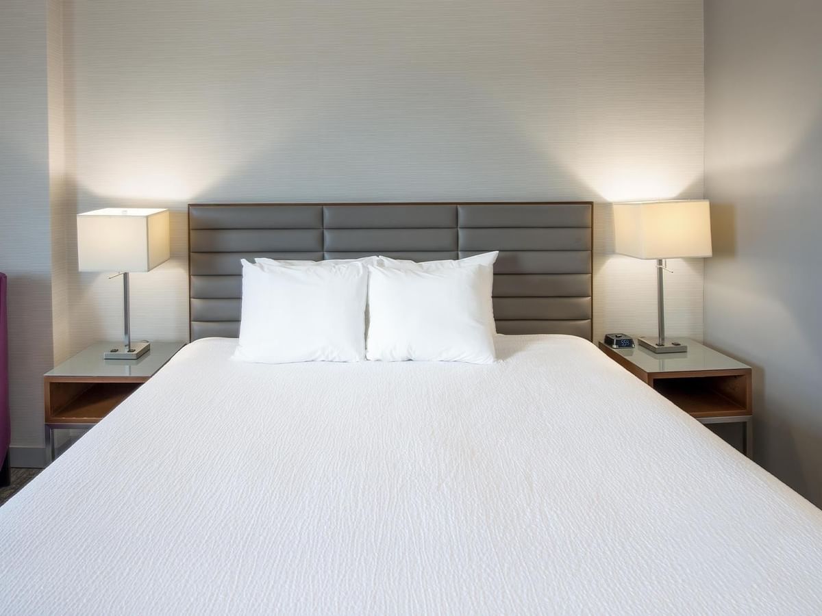 Coast King room with king bed, gray headboard, nightstands, lamps, and purple chair at Coast Prince George Hotel