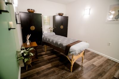 Treatment room with a prepared massage table set between dark wooden cabinets and plant at La Tourelle Hotel and Spa