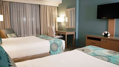 room with two beds and television on wall
