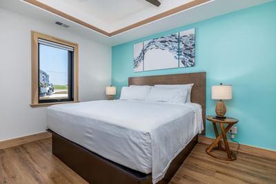 Nightstands beside a cozy bed in the villa, with wooden flooring and decorative wall art at Off Shore Resort