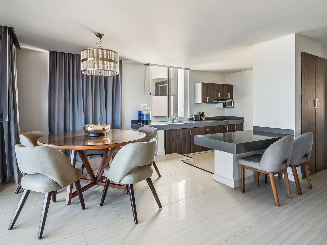 Penthouse featuring a kitchen, dining area with a round wooden table, and grey chairs at Sunvivia Mazatlán