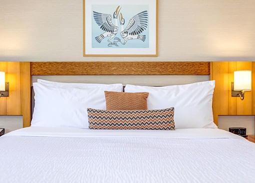 Premium King room with a comfortable white bed, decorative pillows, wooden headboard, and warm bedside lighting