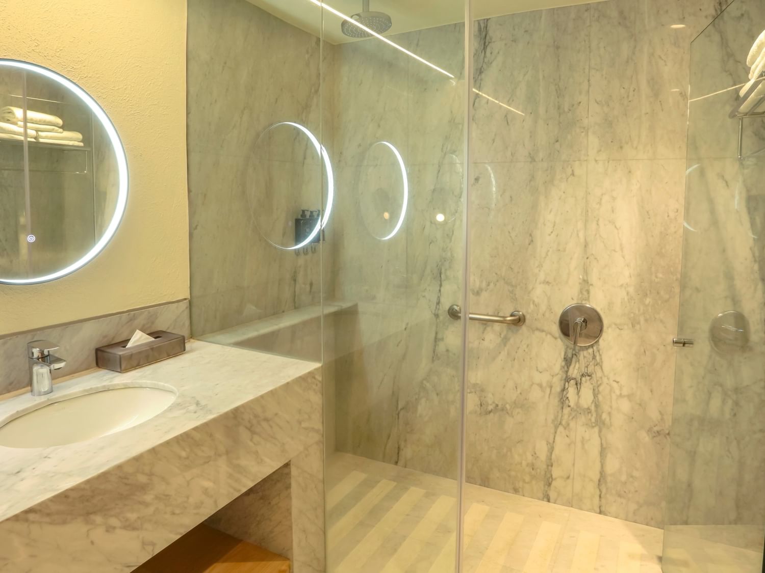 Modern bathroom with a marble sink, large mirror, and glass shower at Camino Real Polanco Mexico in Ciudad de Mexico.