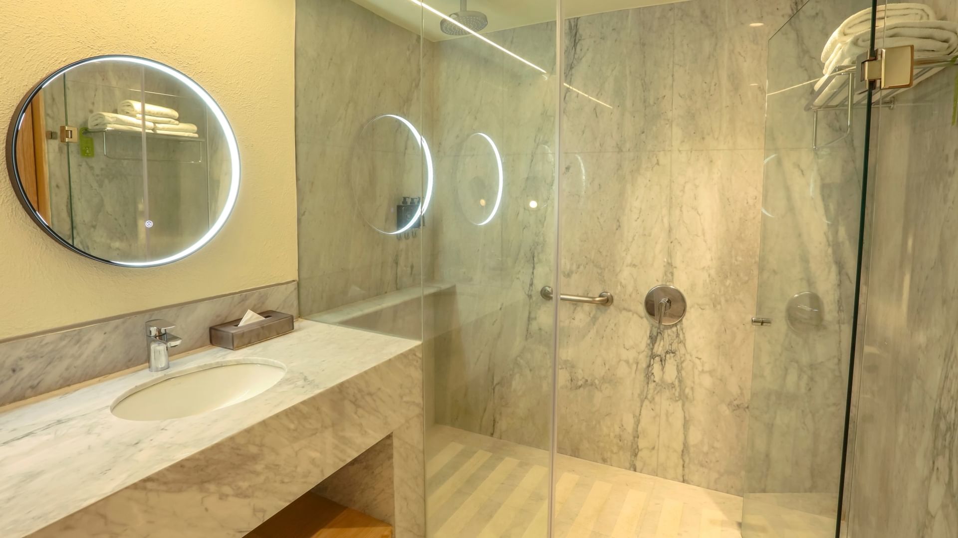 Modern bathroom with a marble sink, large mirror, and glass shower at Camino Real Polanco Mexico in Ciudad de Mexico.