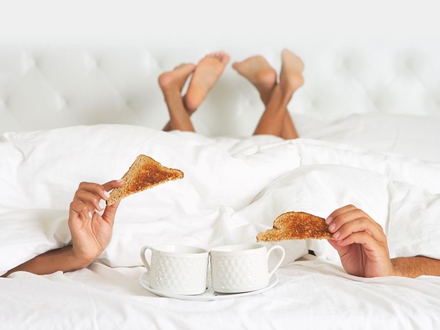 pareja desayunando y tomando café en una cama en el Hotel Delfines