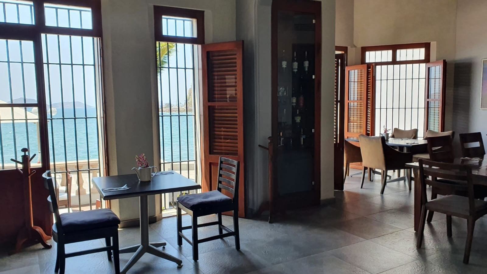 Elegant restaurant interior featuring dining tables and a stunning ocean view from large windows at Curamoria Collection