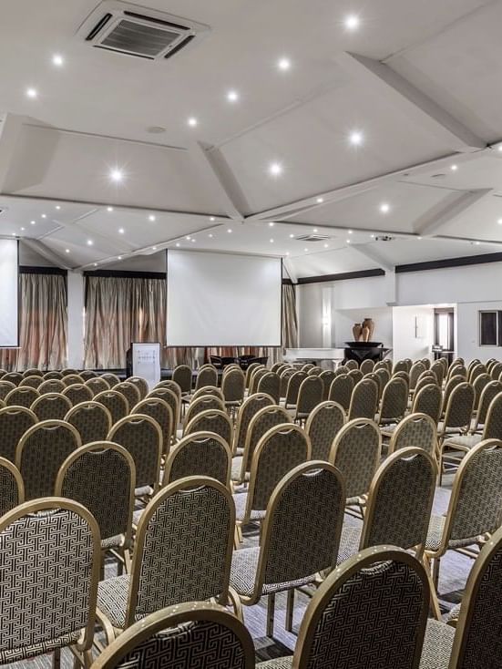 Rows of upholstered chairs by projection screens in Talanoa Hall at Warwick Fiji Resort and Spa