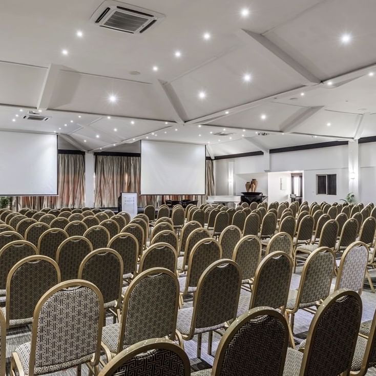 Rows of upholstered chairs by projection screens in Talanoa Hall at Warwick Fiji Resort and Spa