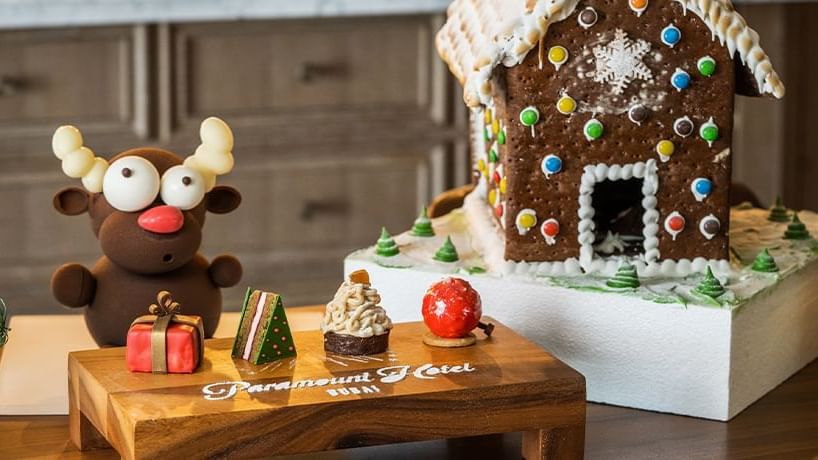 Close-up of festive Christmas snacks near a gingerbread house at Pacific Groove Restaurant, Paramount Hotel Dubai